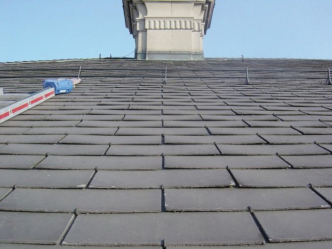 Au lieu de tuiles, un toit est couvert de plaques amiantées gris-brun.