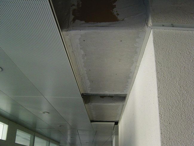 L’habillage d’un plafond a été partiellement retiré. Des plaques de faux plafonds apparaissent.