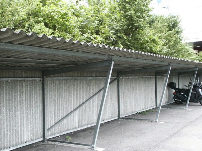 Una pensilina per biciclette con tetto realizzato con i tipici pannelli ondulati contenenti amianto.